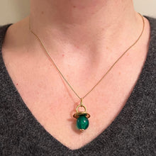 Load image into Gallery viewer, A close-up of a person's neck and chest wearing a delicate gold chain necklace with a pacifier pendant featuring a green bead.
