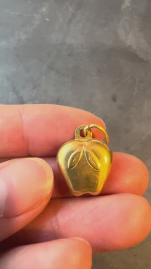 gold apple charm turned in hand on grey background