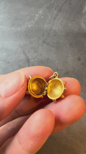 sputnik locket being turned in fingers on grey background