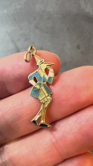 A 9 karat yellow gold charm pendant featuring an enamel depiction of Pinocchio in a blue, black, and white color scheme, with a yellow gold jump ring on top turned in hand