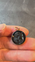 Load and play video in Gallery viewer, A 9K yellow gold charm pendant with an intaglio engraved design of a figure, set in black onyx turned in hand
