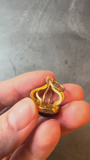 blue and gold pendant turned in hand on grey background