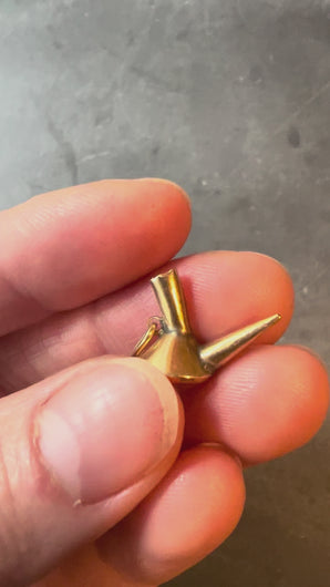 gold porron charm turned in hand on dark background