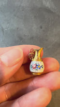 Load and play video in Gallery viewer, Gold pitcher charm with floral design on a grey background turned in hand
