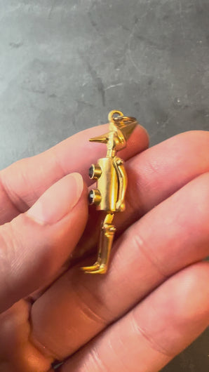 gold man pendant with red buttons turned in hand