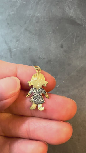 gold and silver doll charm turned in hand on grey background