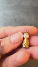 Load and play video in Gallery viewer, Gold pendant with a central pearl turned in hand on a dark background
